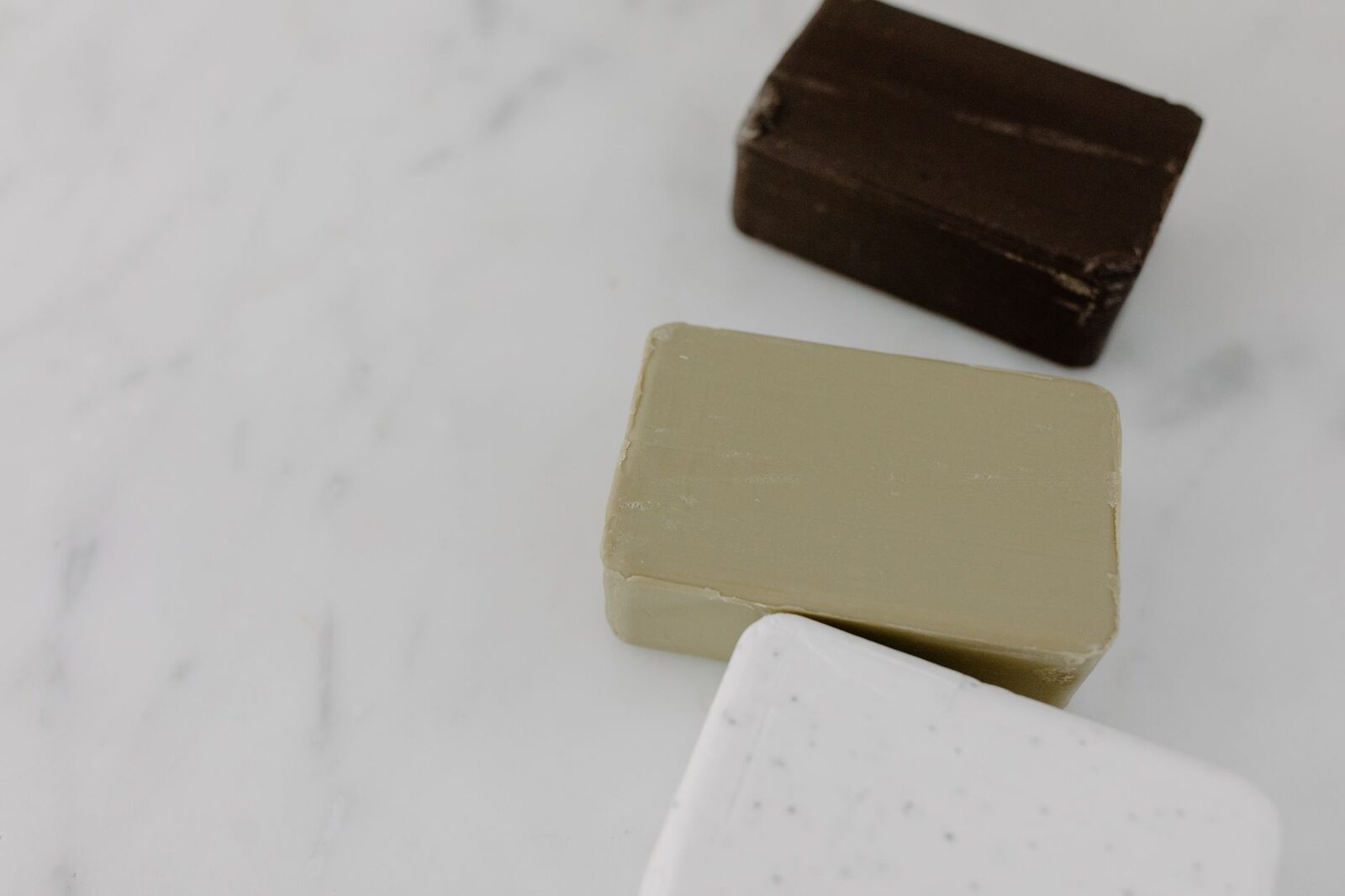 Pains de savon sans parfum posés sur un plan en marbre clair